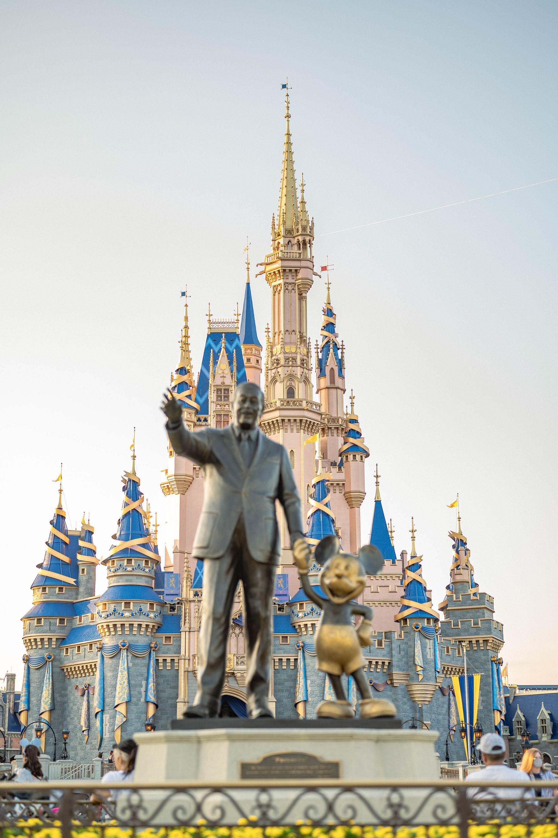 Estatua de Walt Disney con el famoso castillo de fondo